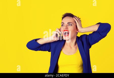 Auf keinen Fall, omg. Gute Nachrichten von Zelle. Porträt der schönen jungen Frau schockiert Gespräch auf Handy isoliert auf gelbem Hintergrund auf der linken Seite von t Stockfoto