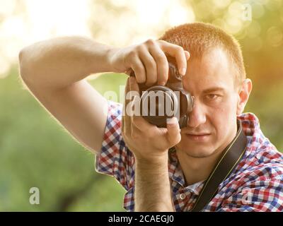 Der Fotograf fotografiert vor dem Hintergrund von Grün. Vorderansicht Stockfoto