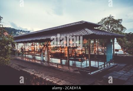 Zwei Menschen brennen Kerzen als traditionelles religiöses Ritual im buddhistischen Zahntempel Stockfoto