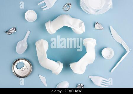 Weißes Recycling-Zeichen aus Kunststoff-Flaschen mit verschiedenen Plastikmüll auf blauem Hintergrund flach lag mit Kopierraum erstellt. Stockfoto