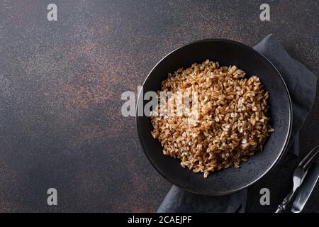 VollkornDinkel in schwarzer Schale auf braunem Hintergrund. Draufsicht. Stockfoto