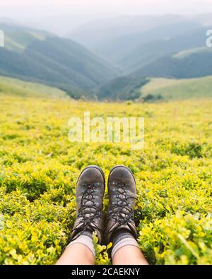 Stiefel von einsamen Touristen auf üppigen Heidelbeer Buschs bedeckten Berg. Landschaftsfotografie Stockfoto