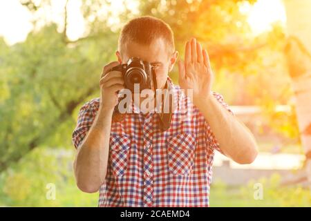 Der Fotograf fotografiert vor dem Hintergrund von Grün. Vorderansicht. Stopp Stockfoto