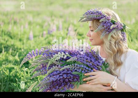 Porträt eines Mädchens mit einem Blumenstrauß in den Händen Lupinen, Blumenstrauß, Konzept der Allergie und Allergiekur, Spa, Erholung. Profil eines Mädchens mit Stockfoto