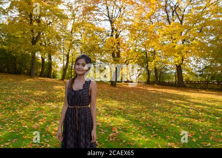 Junge schöne asiatische Frau steht gegen Blick auf den Wald im Herbst Stockfoto