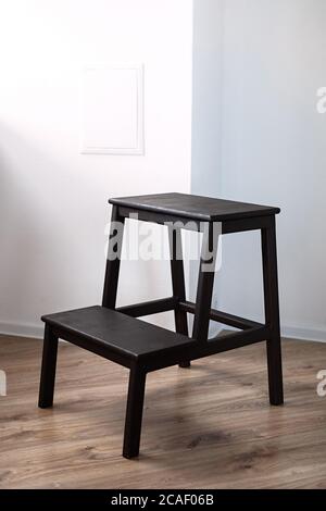 Braune Holztreppe steht im Raum mit weißen Wänden und braunem Boden, Stockfoto