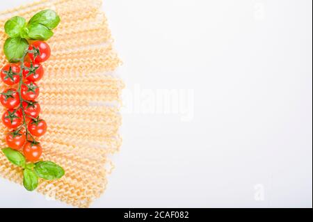 Fusilli lunghi bucati . Lange lockige Pasta auf weißem Teller, mit frischen Basilikumblättern und Kirschtomaten. Traditionelle italienische Pasta aus dem Süden. Hochwertige Fotos. Speicherplatz kopieren Stockfoto