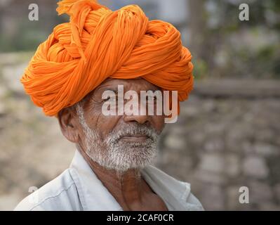 Ältere indische Rajasthani Mann mit orangen Turban (pagari) Posen für die Kamera. Stockfoto