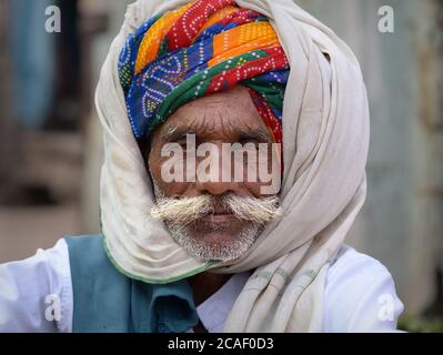 Old Indian Rajasthani Mann mit großen Schnurrbart und bunten Turban (Pagari) bedeckt seinen Kopf und Turban mit einem warmen Wolle Schal / Decke. Stockfoto