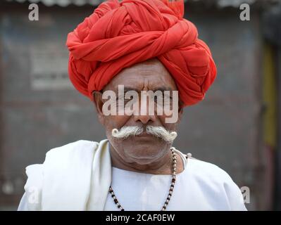 Ältere indische Rajasthani Mann mit roten Turban und großen Schnurrbart Posen für die Kamera. Stockfoto