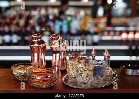 An der Bar befinden sich Gerichte aus rotem Metall, Gerichte zur Cocktailzubereitung, glänzendes Metall, Vasen mit getrockneten Blumen auf einem silbernen Tablett Stockfoto