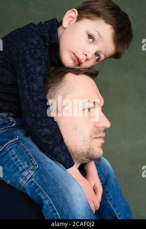 Junge sitzt auf Väter Hals und Umarmungen mit seinen Händen starke Familienbeziehungen, Liebe zum Kind mit heulenden Eltern Stockfoto