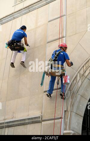 Zwei vertikale Arbeiter bei Solver Soluciones verticales, die an Kletterseilen hängen und eine Fassade oder ein Außengebäude in Granada, Spanien, renovieren. Stockfoto