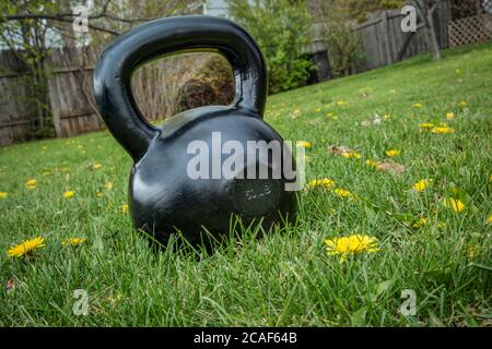 Eisen Kettlebell auf grünem Gras in einem Hinterhof, niederländischen Winkel erschossen - Outdoor-Fitness-Konzept Stockfoto