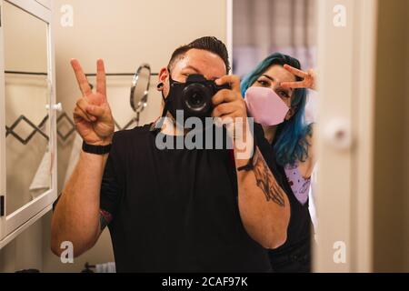 Männlich und weiblich nehmen ein Selfie tun das "Friedenszeichen" Pose auf einem Badezimmerspiegel Stockfoto