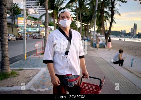 Küchenchef aus einem japanischen Restaurant, noch in seiner Arbeitsuniform, macht sich nach der Arbeit auf den Weg nach Hause. Thailand Südostasien Stockfoto