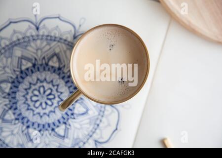 Dekoratives rundes Blumenmandala auf weißem Blatt gezeichnet. Home Entspannung, Hobby und Erholung. Kaffee und Kekse auf weißem Hintergrund. Stockfoto