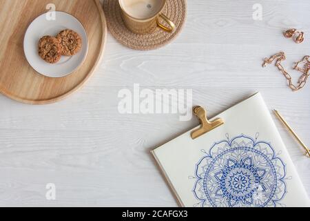 Dekoratives rundes Blumenmandala auf weißem Blatt gezeichnet. Home Entspannung, Hobby und Erholung. Kaffee und Kekse auf weißem Hintergrund. Stockfoto