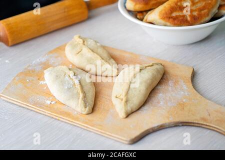 Nicht gebratene Kuchen liegen auf Holzbrett. Hausmannskost. Backen zu Hause. Stockfoto