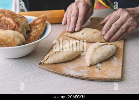Oma kocht Torten. Hausgemachte Speisen. Omemade Kuchen des Teiges in die Hände der Frauen. Der Prozess der Herstellung Kuchen Teig mit der hand Stockfoto