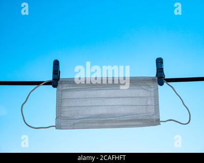 Die medizinische Gesichtsmaske trocknet auf einer Wäscheleine. Stockfoto