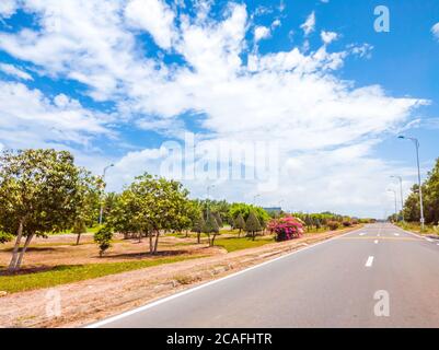 Schöne Aussicht auf breite offene Straße mit einer gepflasterten Autobahn erstreckt sich so weit das Auge kann mit kleinen grünen Hügeln, rosa Blumen unter einem hellen sehen Stockfoto