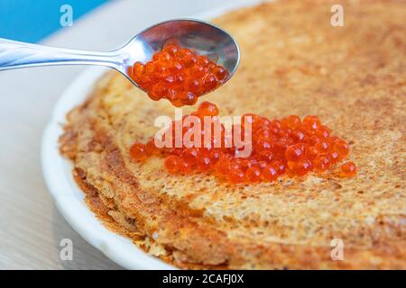 Pfannkuchen auf einem Teller mit rotem Kaviar und Löffel. Stockfoto