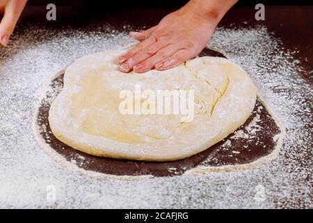 Frau glättet Teig mit ihren Händen für die Herstellung von Pizza. Stockfoto