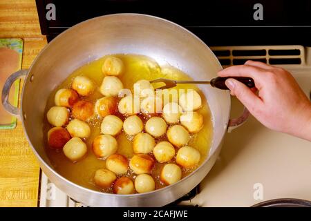 Frau dreht und frites rund Knabenkinder in heißem Öl. Stockfoto