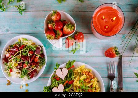 Bunte Rotini-Pasta mit gesundem Frühlingssalat und frischen Erdbeeren auf Holzgrund. Stockfoto