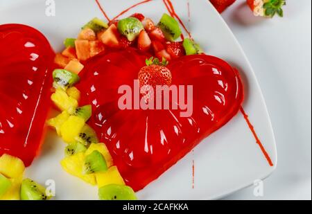 Erdbeergelatine mit frischer Erdbeere, Kiwi und Ananas verziert. Dessert am Valentinstag. Stockfoto