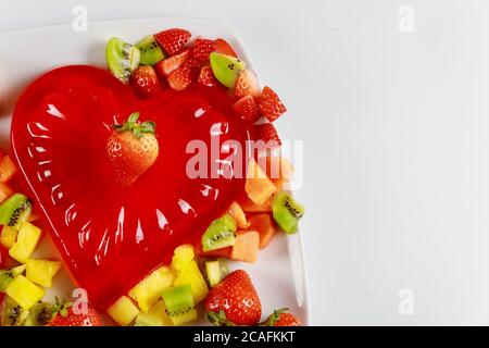 Rote Gelatine mit gehacktem frischem Obst auf weißem Hintergrund. Valentinstag. Stockfoto