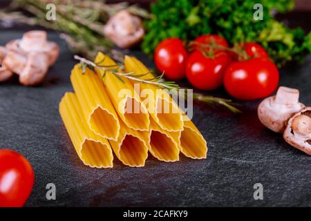 Rohe große Pasta Manicotti mit Tomaten, Pilzen und Rosmarin. Stockfoto