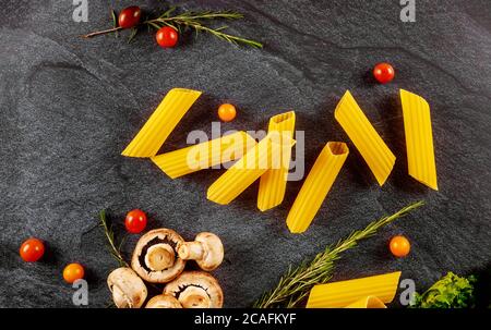 Bio Pasta Manicotti mit Pilzen und Tomaten auf schwarzem Hintergrund. Stockfoto