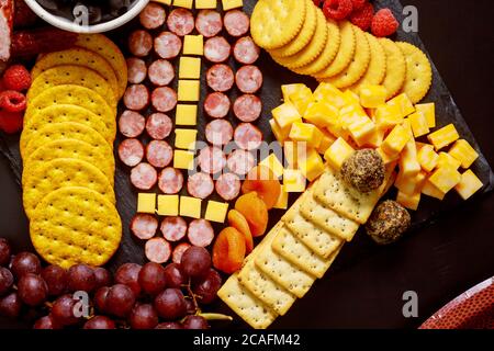 Fußball aus Käse und Wurst für Wurstwaren auf Holzhintergrund. American Football Spiel Konzept. Stockfoto