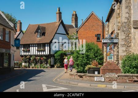 Wymondham Norfolk, Blick im Sommer von zwei reifen Frauen, die in Richtung des Green Dragon Pub im Zentrum von Wymondham Stadt, Norfolk, Großbritannien gehen Stockfoto