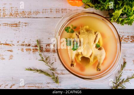 Hühnerbrühe mit Karotten, Hähnchen, Zwiebeln, Sellerie und Petersilie im glassl-Topf. Stockfoto