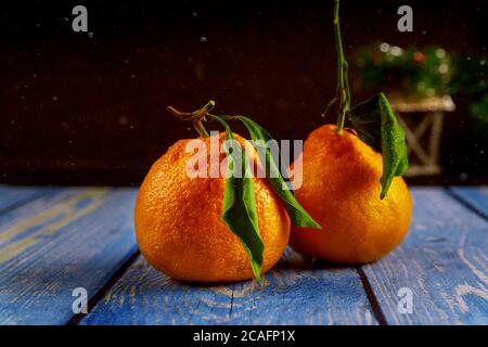 Zwei Mandarinen mit grünem Blatt auf Holztisch. Stockfoto