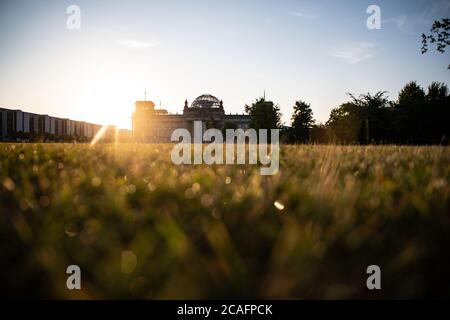 Berlin, Deutschland. August 2020. Die aufgehende Sonne lässt den Rasen vor dem Reichstagsgebäude leuchten. Quelle: Paul Zinken/dpa-Zentralbild/dpa/Alamy Live News Stockfoto