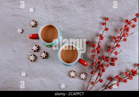 Zwei Tassen Kaffee auf weißem Tisch mit rotem Beerenzweig und Ingwerkeks. Stockfoto