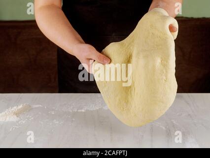 Person, die Pizzateig in den Händen knetet, um Pizza zu machen. Stockfoto