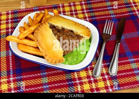 Steak und Kidney Pie und Chips Mahlzeit mit matschigen Erbsen In einer Metall-Emaille-Schale Stockfoto