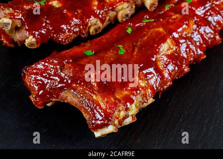 BBQ Schweinefleisch Spare Ribs auf schwarzem Brett Nahaufnahme. Stockfoto