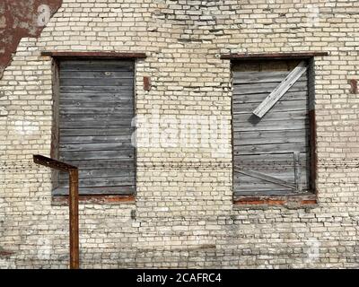 Altes verlassene Ziegelgebäude mit vernagelten Fenstern aus der Nähe Stockfoto