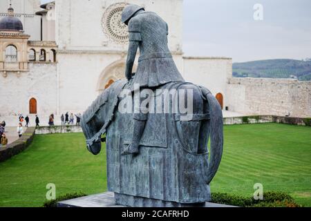 Assisi, italien - juni 30 2020: Berühmte Bronzeskulptur vor der kirche des heiligen franziskus von Assisi mit Pilgern, die Italien besuchen Stockfoto