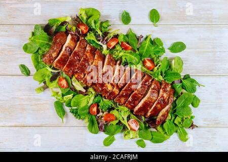 Aufschnitt BBQ Schweinelende Filet servieren mit grünem Salat und Tomaten. Stockfoto