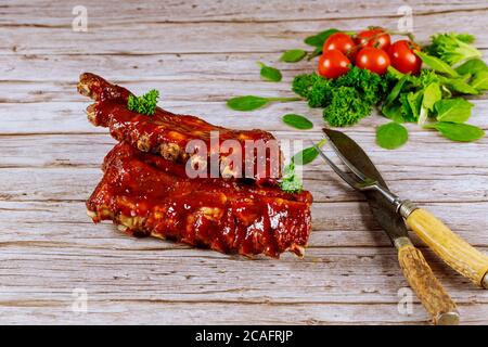 Schweinefleisch Rippchen gegrillt mit BBQ-Sauce , Tomaten und Spinat auf Holzgrund. Stockfoto