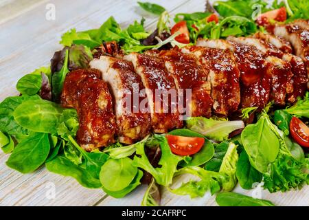 Leckere BBQ-Rippchen mit Tomaten, grünem Salat und würziger BBQ-Sauce. Stockfoto