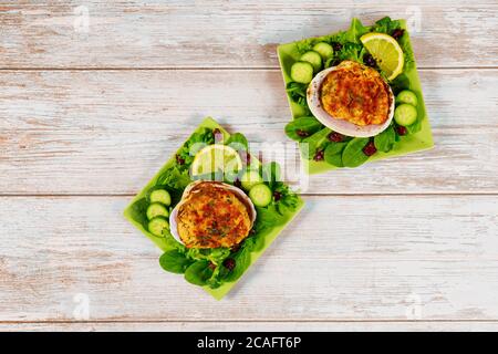 Meeresfrüchte-Gericht mit gefüllten Muscheln und frischen Salat auf Holzhintergrund. Stockfoto