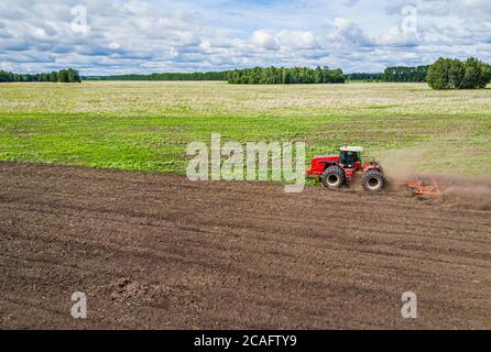 Große landwirtschaftliche Maschine bewirtschaftet das Land. Der Blick von oben. Pflügen Land für die Pflanzung von Pflanzen. Fotos aus der Vogelperspektive mit Stockfoto